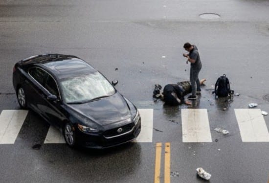 A daytime street scene showing a pedestrian accident at a crosswalk in a Texas city