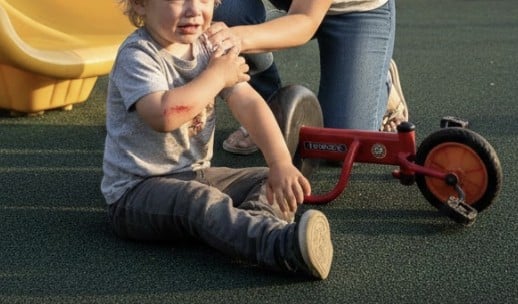 A daytime playground accident scene in a suburban park.